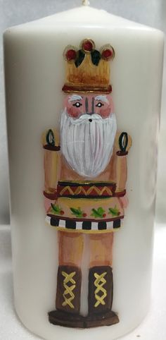 a white candle with a painted nutcracker on it's front and sides