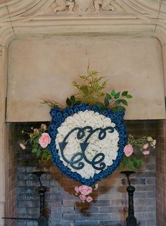 a fireplace decorated with flowers and a monogrammed sign