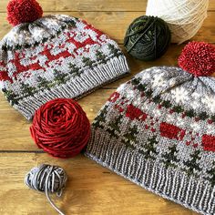 two knitted hats sitting on top of a wooden floor next to balls of yarn