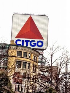 a large citgo sign sitting on top of a tall building next to trees