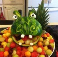 a watermelon head made to look like a frog with fruit in it's mouth