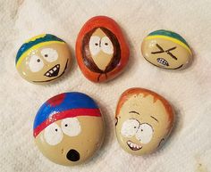 five painted rocks with cartoon faces on them sitting on a white towel in the shape of eggs