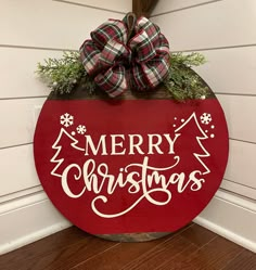 a merry christmas sign hanging on the side of a house with a bow in it