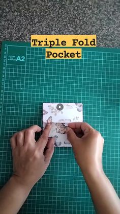 a person cutting up a piece of paper on top of a green cutting mat with the words triple fold pocket