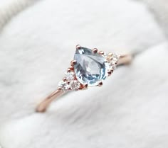 an engagement ring with a blue topazte surrounded by white and rose gold diamonds