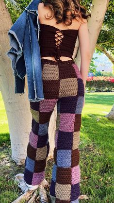 a woman standing next to a tree wearing plaid pants