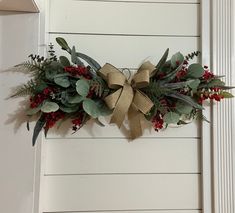 a christmas wreath hanging on the side of a white door with red berries and greenery