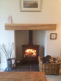 a wood burning stove sitting inside of a living room next to a basket filled with flowers