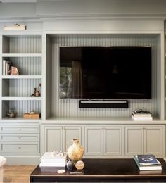 a living room with built in bookshelves and a flat screen tv mounted on the wall