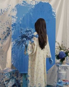 a woman standing in front of a blue painting