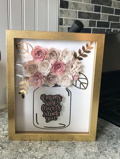 some paper flowers are in a gold frame