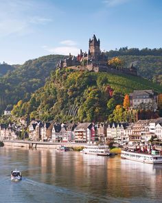 a castle on top of a hill next to a body of water with boats in it