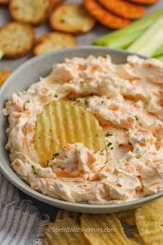 a bowl full of dip with crackers and celery