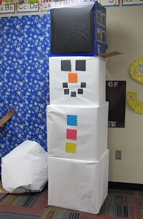 a snowman made out of cardboard sitting in front of a blue and white wall