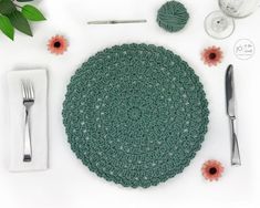 a crocheted placemat and silverware on a table