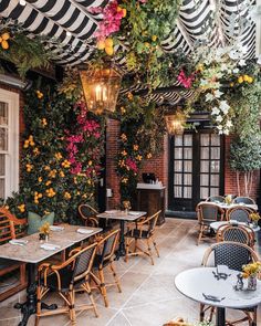 an outdoor dining area with tables, chairs and flowers hanging from the ceiling over them