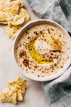 a white bowl filled with dip surrounded by crackers