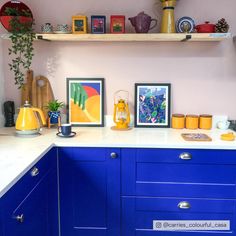 a kitchen with blue cabinets and pictures on the wall above it's countertop