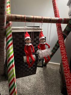 two elfs are hanging from the ceiling in their christmas themed room, one is on a swing