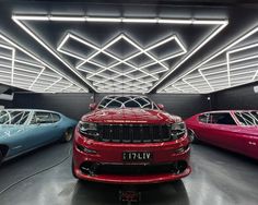 three different colored cars parked in a garage