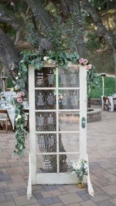 an old window is decorated with flowers and greenery for a wedding ceremony at the park