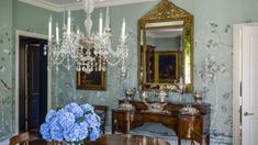 a dining room table with blue flowers on it and a chandelier hanging from the ceiling