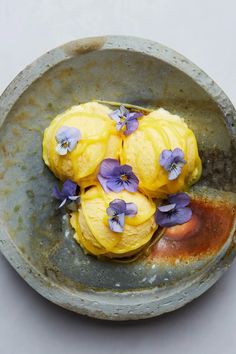 some yellow and purple flowers are in a bowl