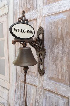 an old fashioned welcome sign with a bell attached to it