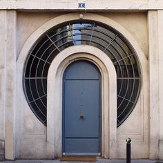 a blue door is in front of an arched window on the side of a building