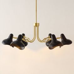 three black lamps hanging from a brass chandelier in a room with white walls