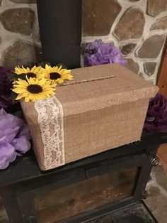 a brown box with white lace and sunflowers sitting on top of it next to purple flowers