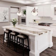 a large kitchen island with stools in the middle and two pendant lights hanging over it