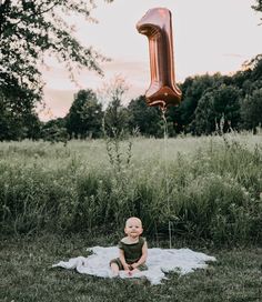 a baby sitting on a blanket with a balloon in the shape of an i - letter