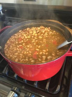 a red pot filled with beans on top of an open stove burner next to the oven