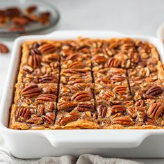 a white dish filled with pecan squares on top of a table