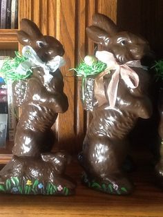 two chocolate bunnies sitting on top of a wooden shelf