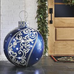 a blue and white christmas ornament sitting on the ground in front of a door