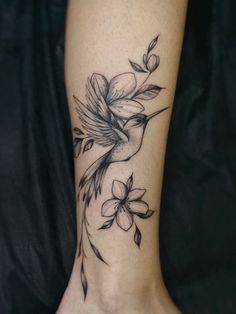 a woman's foot with flowers on it and a bird flying over the flower