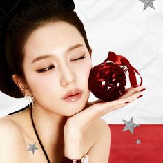 a woman holding a red heart shaped object in front of her face with stars on the background