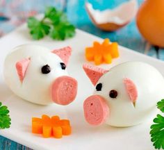 two pigs made out of marshmallows and carrots on a white plate