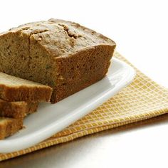 sliced loaf of bread sitting on top of a white plate next to a yellow and white napkin