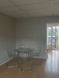 an empty room with a glass table and chairs