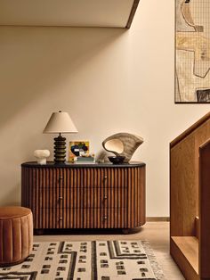 a living room with a rug, table lamp and art on the wall above it