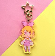 a keychain shaped like a cartoon character on a pink and yellow striped background