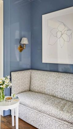 a living room with blue walls and white furniture in the corner, along with a painting on the wall