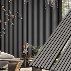 a living room filled with furniture next to a tall black wall covered in hanging birds