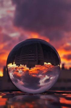 a glass ball with the reflection of buildings and clouds in it is shown at sunset