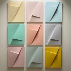 six different colored paper squares arranged in the shape of an origami triangle on a wall