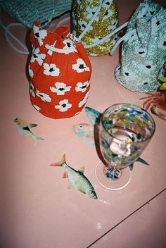 there are many fish on the table next to some glasses and bags with sequins