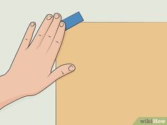 a hand with a blue eraser on top of a piece of paper that is taped to the wall